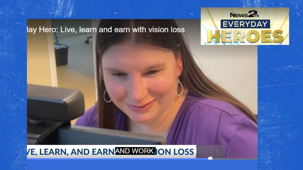 A woman smiles while looking at a computer screen. Logo for channel 2 Everyday Hero sits at top right. Headline below reads Live, learn, earn with vision loss.