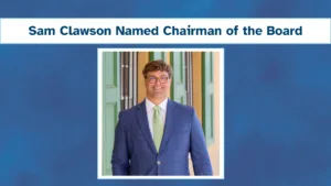 Photo of Sam Clawson smiling, dressed in blue suit jacket
