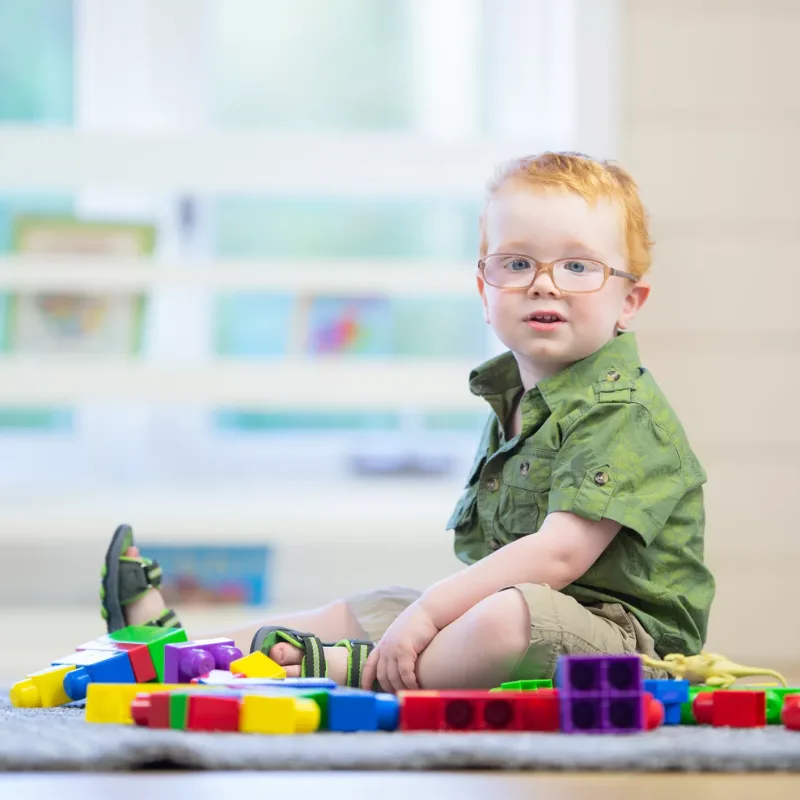 A child sits and plays with building blocks happily.