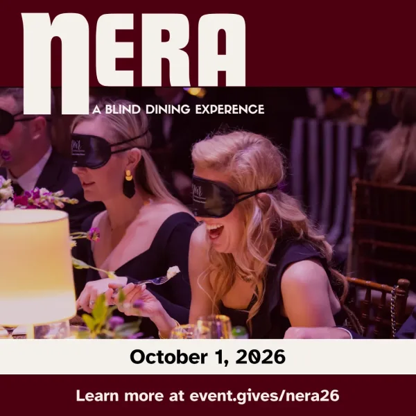 Photo of a woman at a formal dining event, enjoying her meal while wearing a blindfold. She's seated at a table with other guests. Text overlayed on photo reads Nera, a blind dining experience.