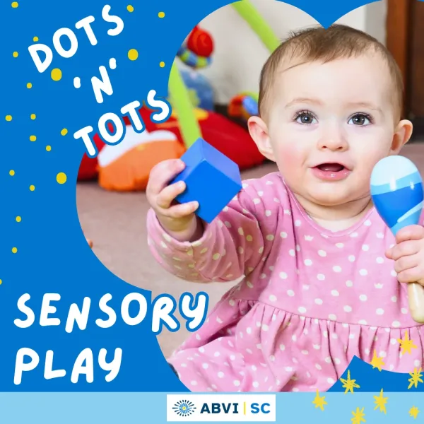 Sensory Play Dots N Tots A flower shaped border outlines the photo of a baby girl holding up a blue rattle and blue block. White text on a blue background reads "Dots 'N' Tots" Sensory Play."